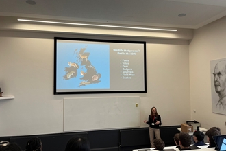 A women delivering a talk in front of a big screen showing a map of the UK