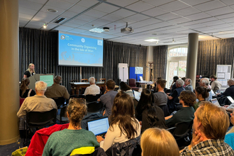 a group of people gathered in a room, listening to a presentation