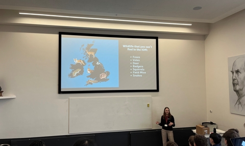 A women delivering a talk in front of a big screen showing a map of the UK