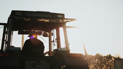 An image of the back of a farmer in a tractor