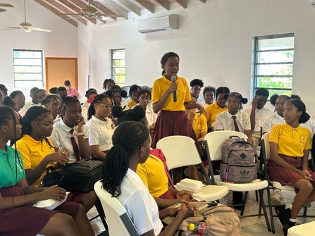 Students from Montserrat Secondary School sat in an audience with one girl holding a microphone