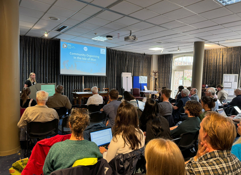 a group of people gathered in a room, listening to a presentation